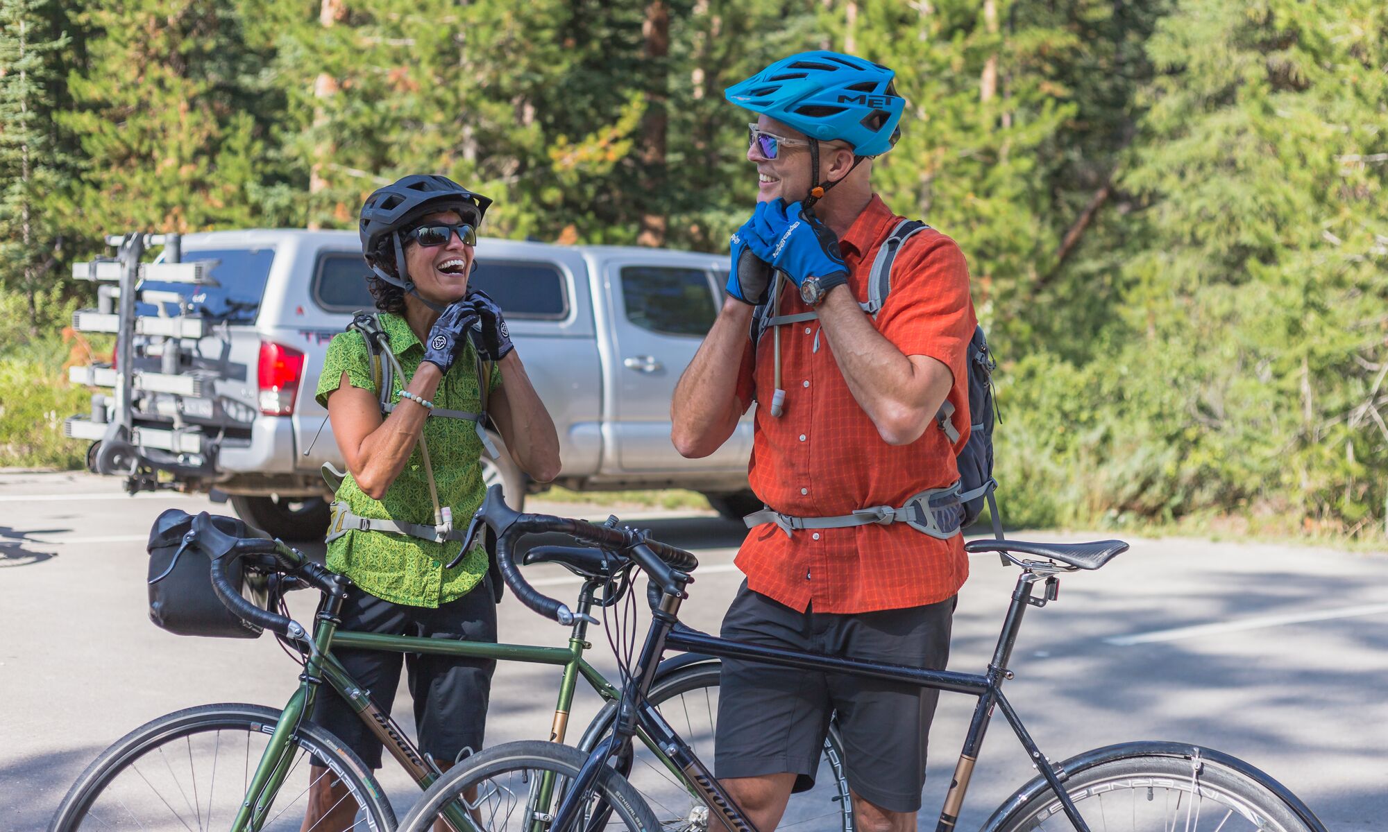 Two cyclists buckle up their helmets before heading out biking in Banff National Park.