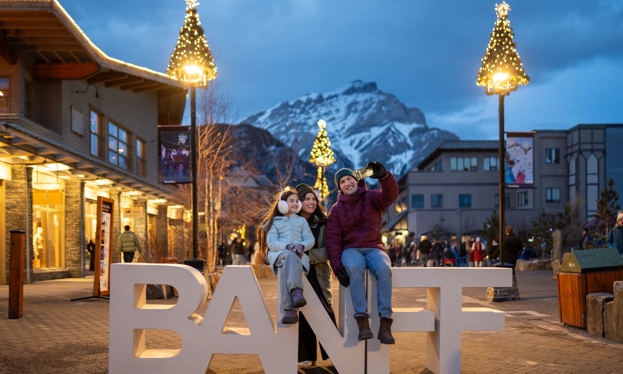 A family taking a photo with a Banff sign on Bear Street in Banff National Park
