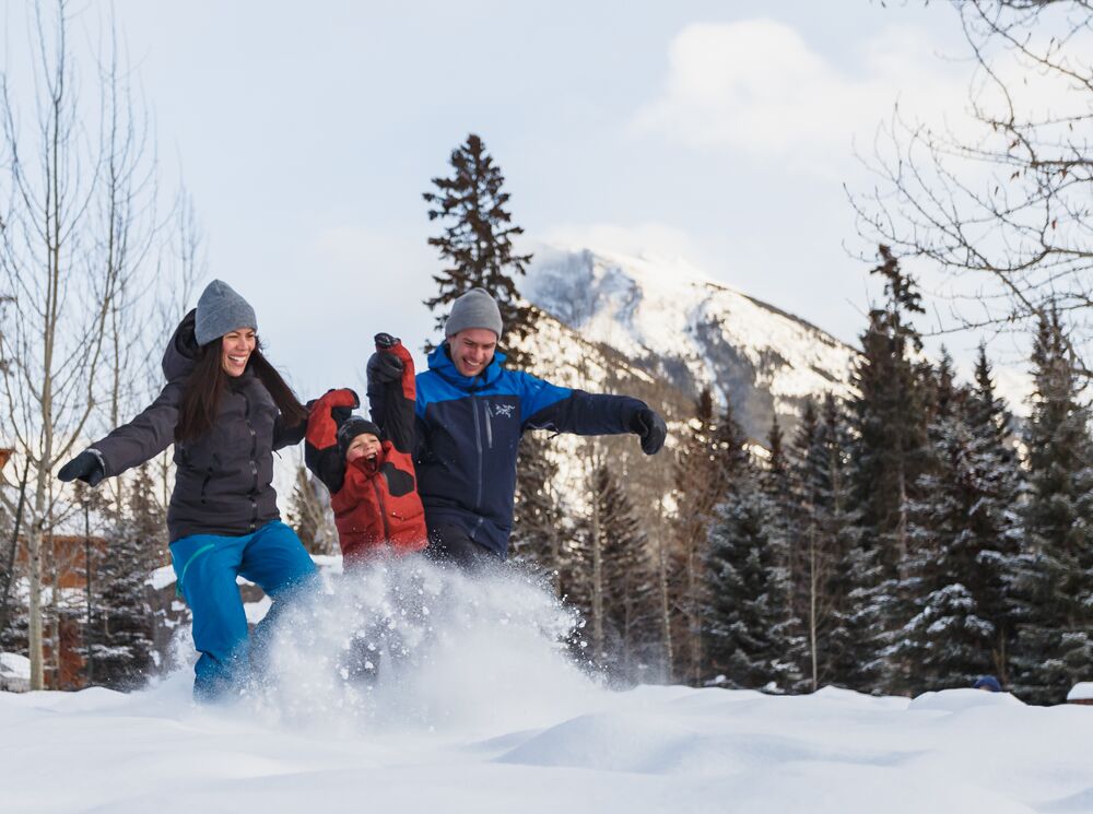 A family of three playing in the snow in Banff National Park