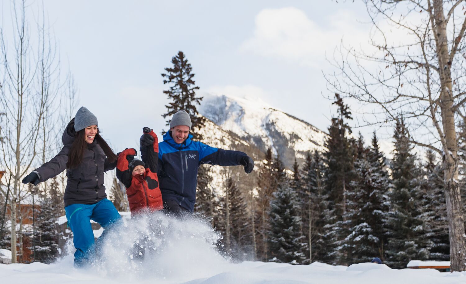 A family of three playing in the snow in Banff National Park