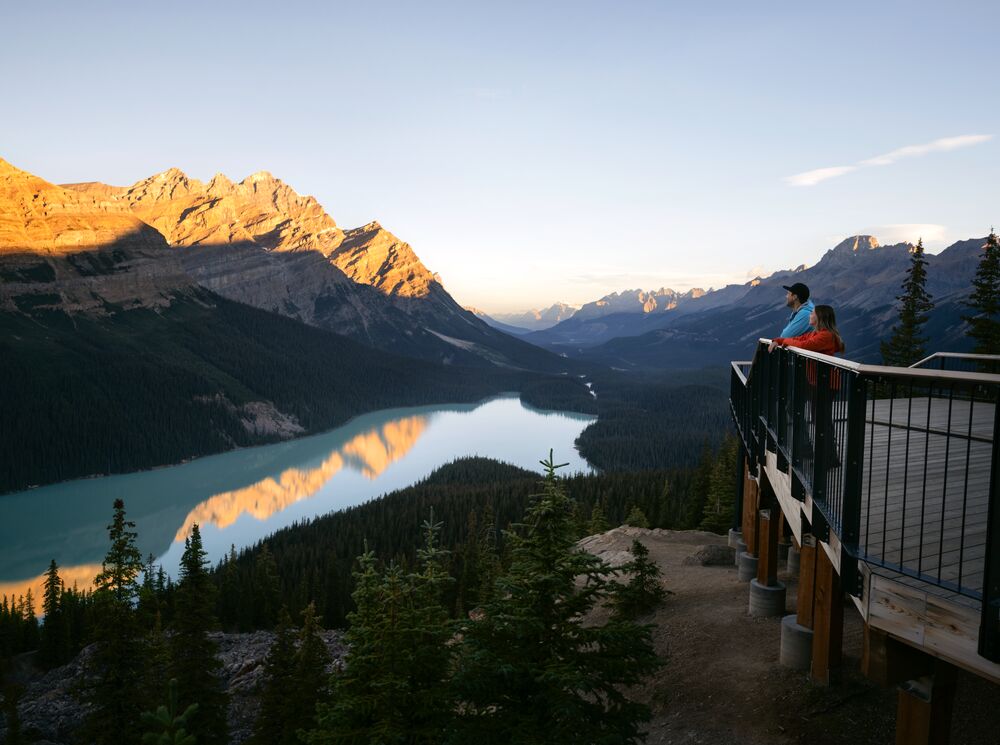 Two people stand at a viewpoint over looking Peyto Lake after hiking in Banff National Park.
