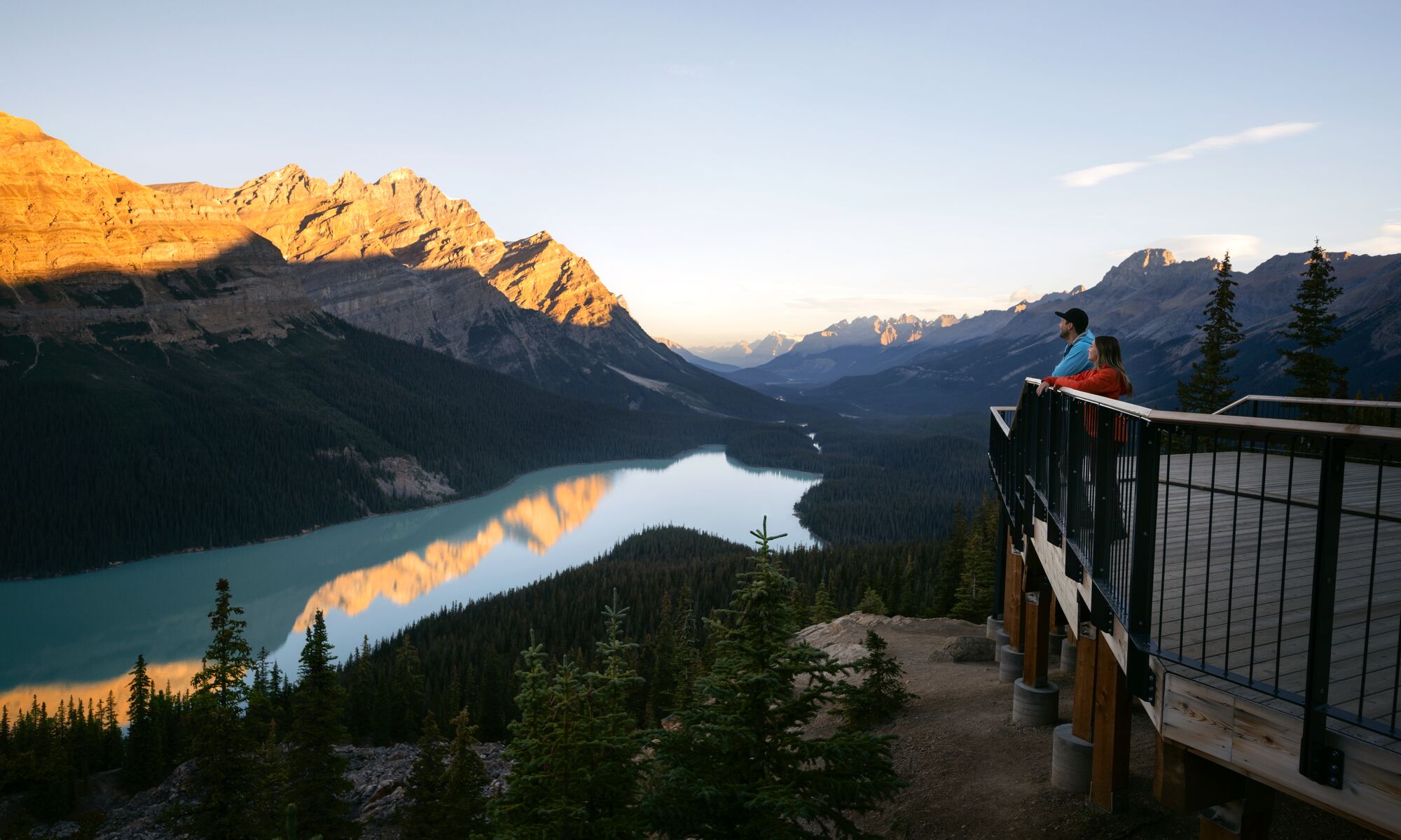 Two people stand at a viewpoint over looking Peyto Lake after hiking in Banff National Park.
