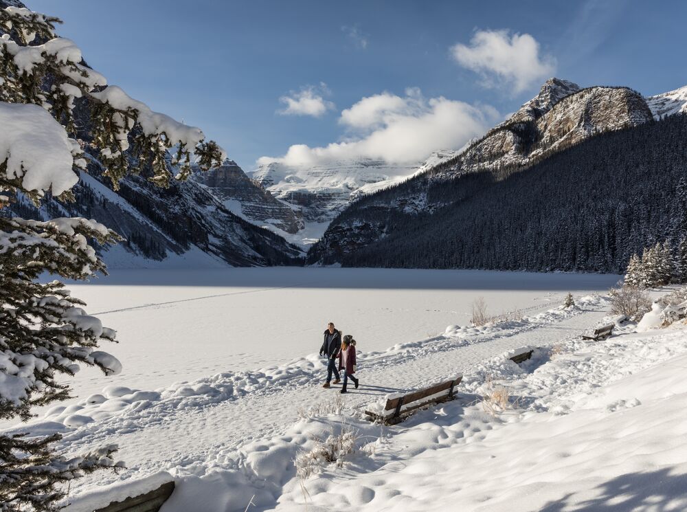 A couple walking along the Lake Louise Lakeshore trail in Banff National Park in winter