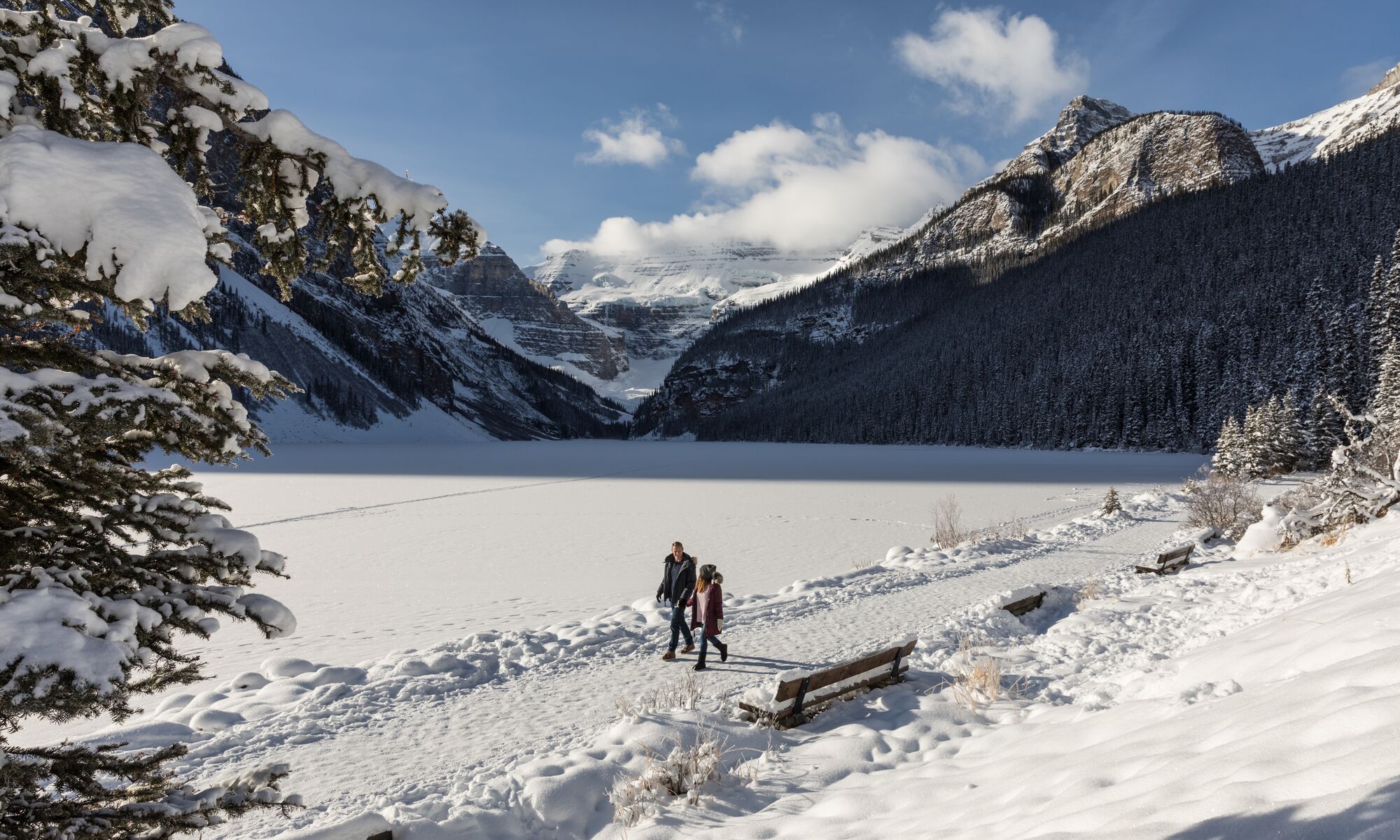 A couple walking along the Lake Louise Lakeshore trail in Banff National Park in winter