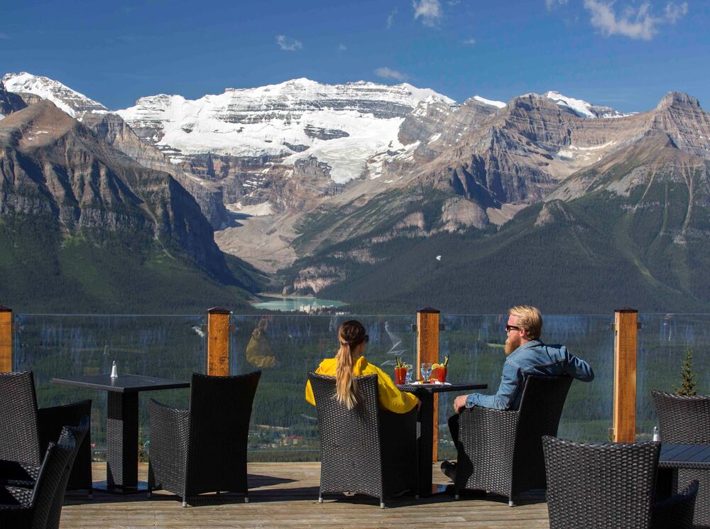Two people sit at Whitehorn Bistro on a sunny summer day at the Lake Louise Ski Resort after biking the Bow Valley Parkway in Banff National Park.