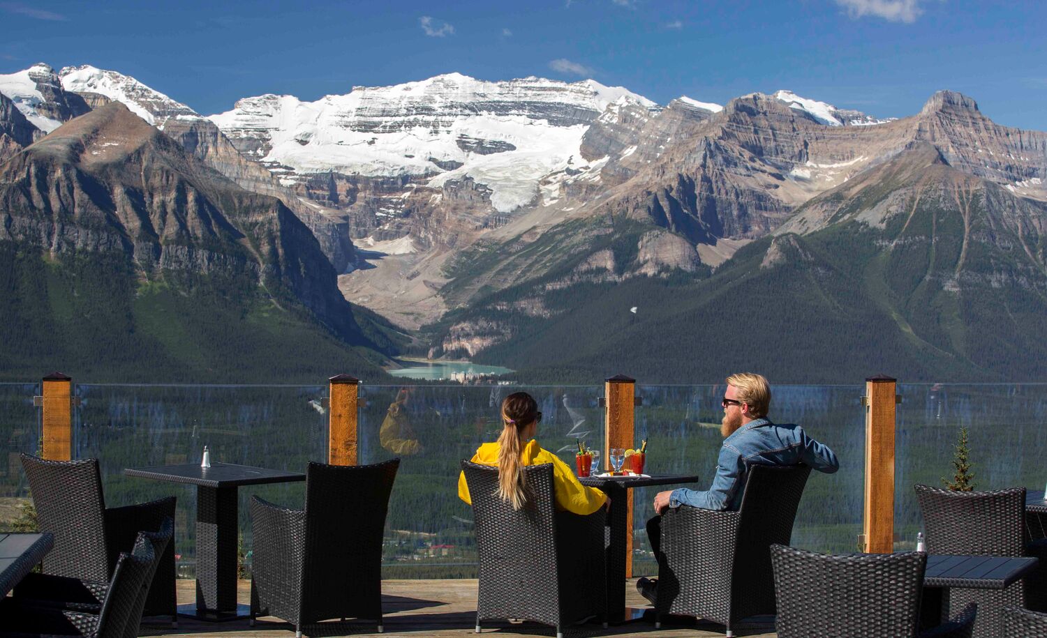 Two people sit at Whitehorn Bistro on a sunny summer day at the Lake Louise Ski Resort after biking the Bow Valley Parkway in Banff National Park.