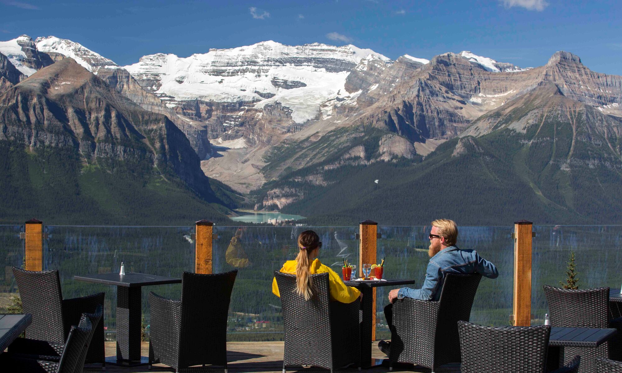 Two people sit at Whitehorn Bistro on a sunny summer day at the Lake Louise Ski Resort after biking the Bow Valley Parkway in Banff National Park.