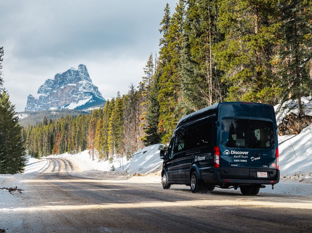 A Discover Banff Tours van driving on the Bow Valley Parkway in Banff National Park
