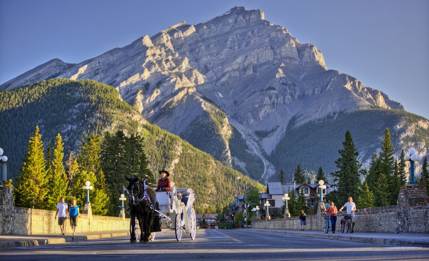 A horse-drawn carriage going down Banff Ave with Cascade Mountain in the back in Banff National Park