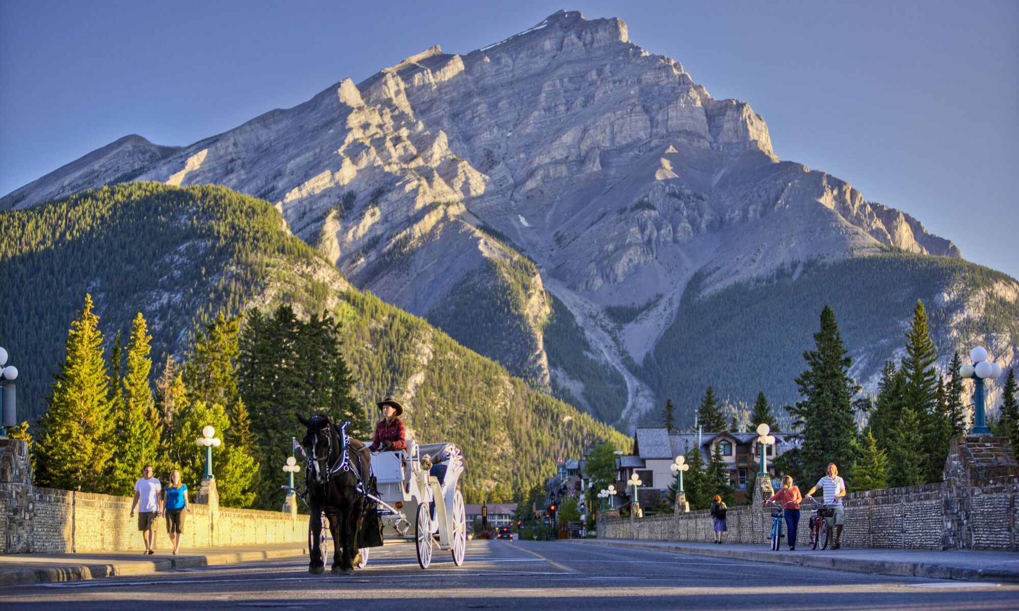 A horse-drawn carriage going down Banff Ave with Cascade Mountain in the back in Banff National Park