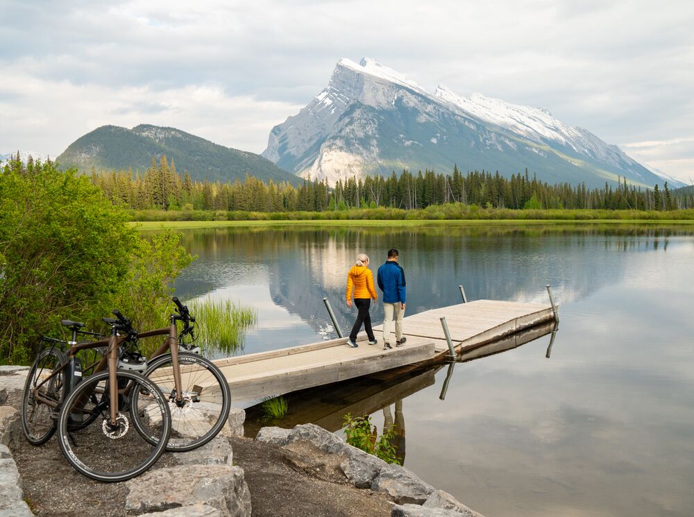 Two people stand at the end of a dock at Vermilion Lakes in Banff after
