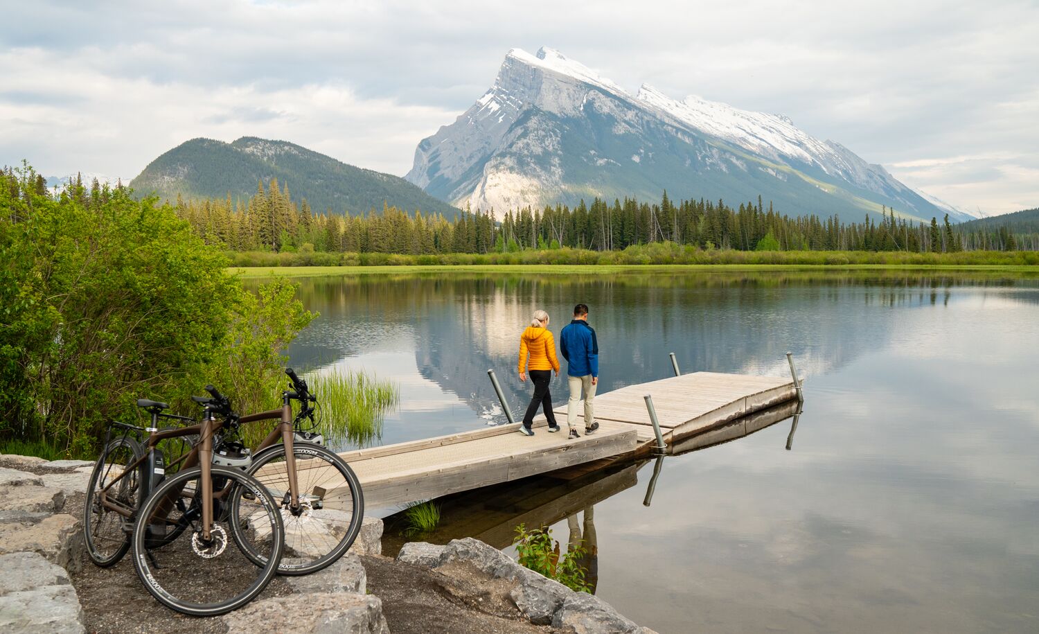 Two people stand at the end of a dock at Vermilion Lakes in Banff after