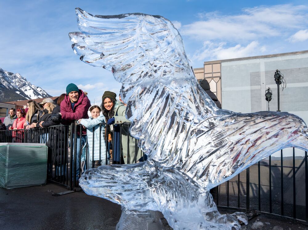 A family looking at an ice sculpture at art of ice during the SnowDays festival in Banff National Park