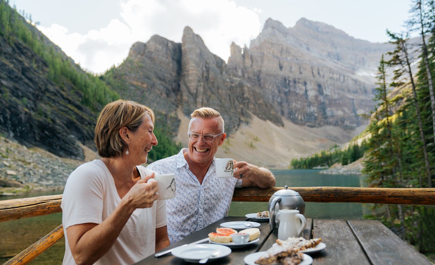 A couple sits at a picnic table at the Lake Agnes Tea House after hiking in Banff National Park.
