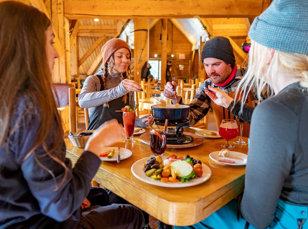 A group of friends eating fondue at the Lake Louise Ski resort in Banff National Park