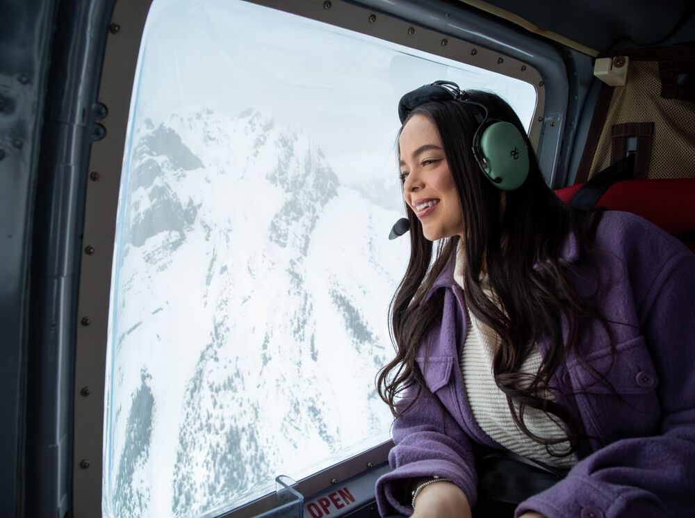 A girl in a helicopter looking out onto the snowy mountains in Banff National Park