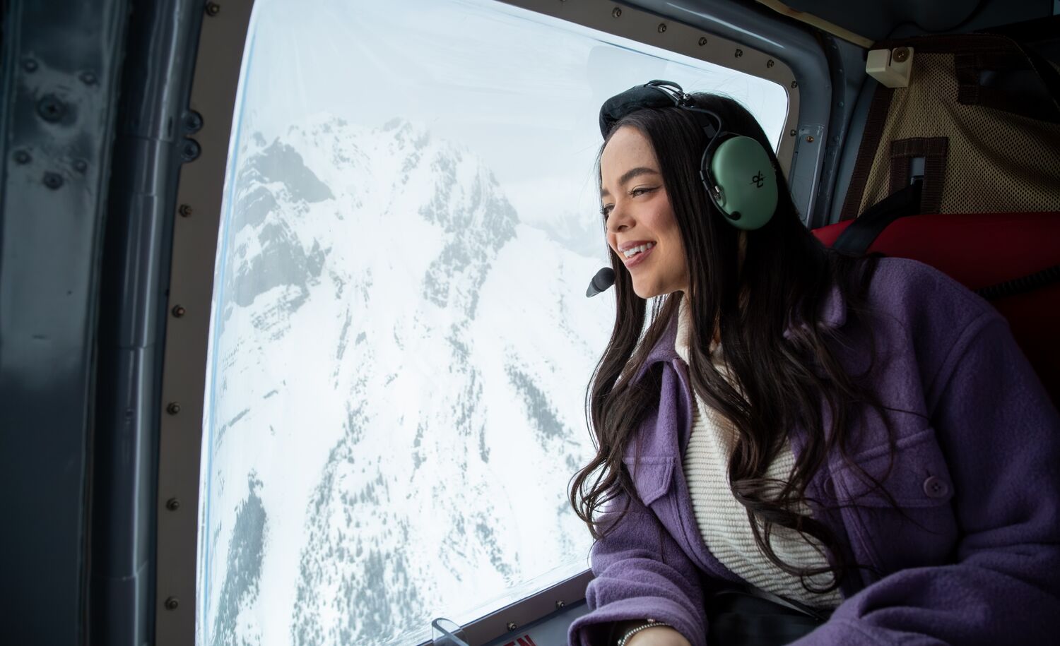 A girl in a helicopter looking out onto the snowy mountains in Banff National Park