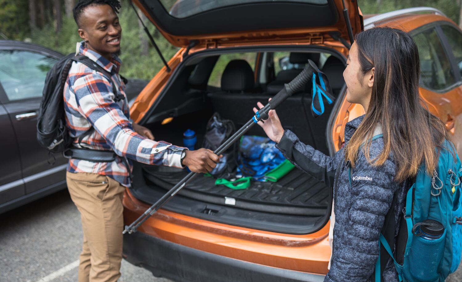 A person hands a hiking pole to another person from a vehicle while they get ready for hiking at Lake Minnewanka in Banff National Park.