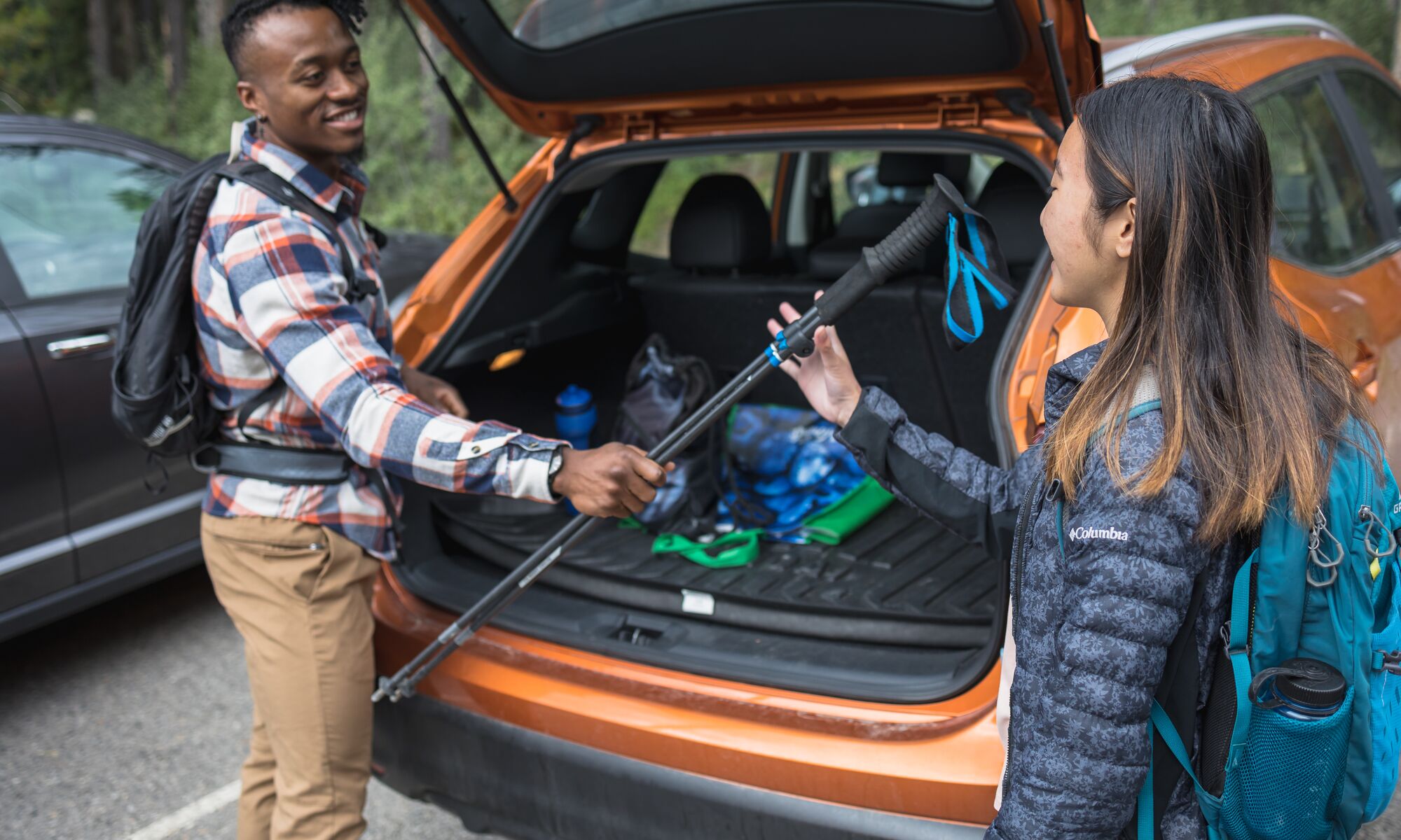 A person hands a hiking pole to another person from a vehicle while they get ready for hiking at Lake Minnewanka in Banff National Park.