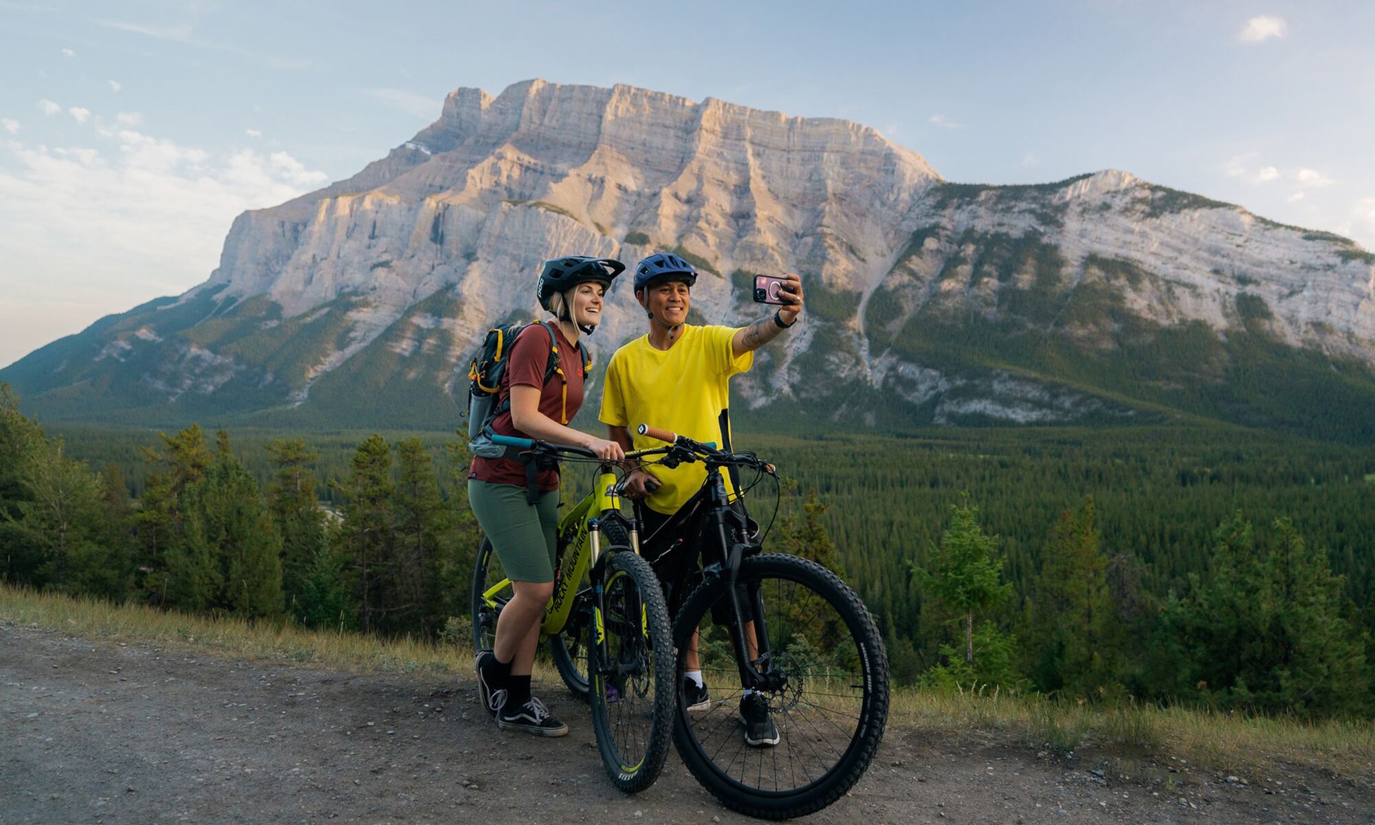 Two people take a photo while mountain biking in Banff at the Tunnel Mountain Trail.