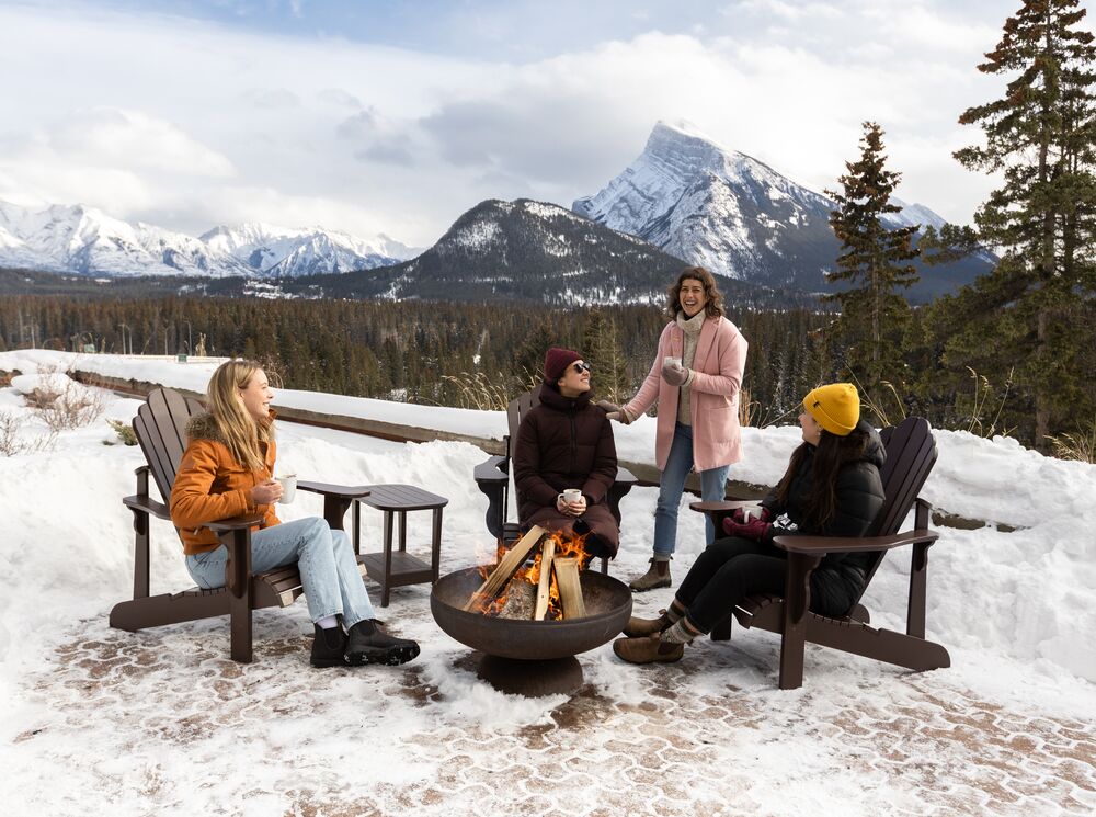 Four women sit around a firepit at the Juniper Bistro in Banff National Park