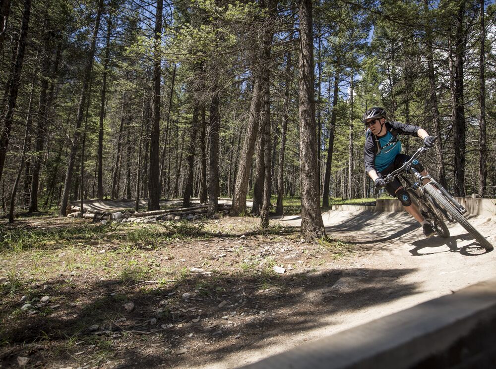 A mountain biker slides around a berm on the Tunnel Mountain Technical Trails for mountain biking in Banff.
