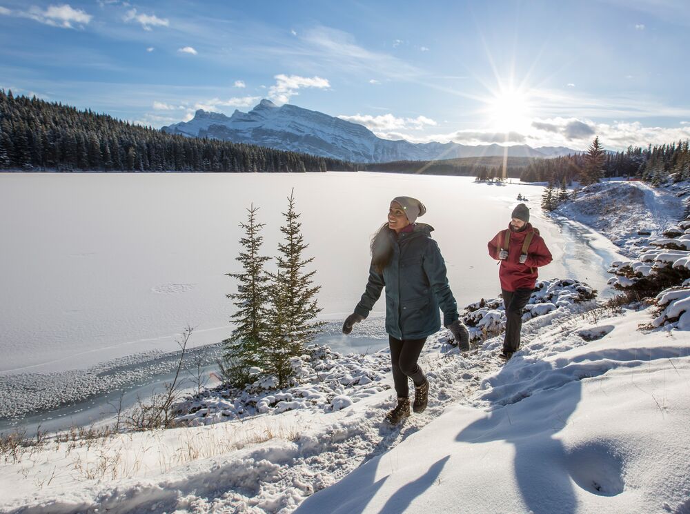 A couple hiking along Two Jack Lakeshore in the winter in Banff National Park