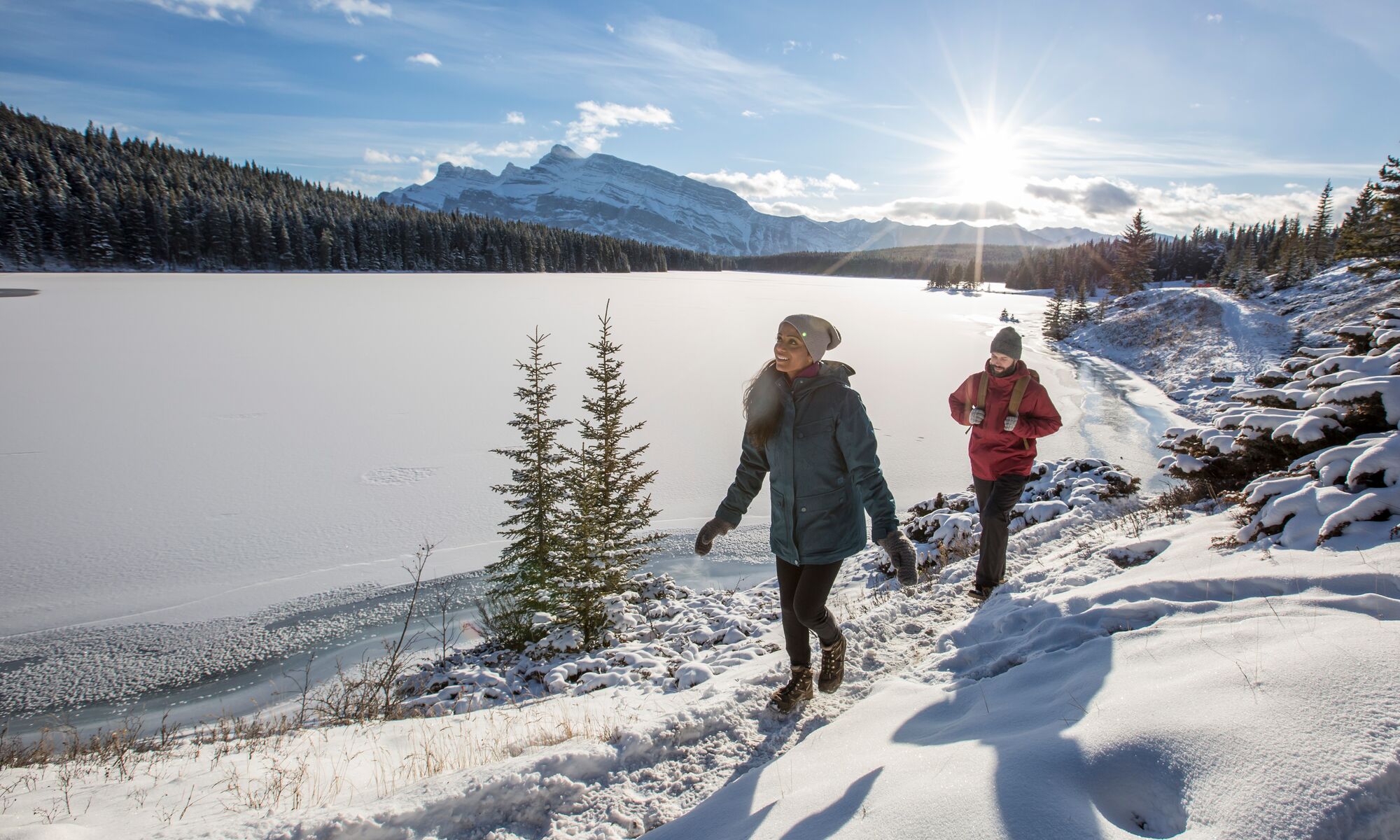 A couple hiking along Two Jack Lakeshore in the winter in Banff National Park