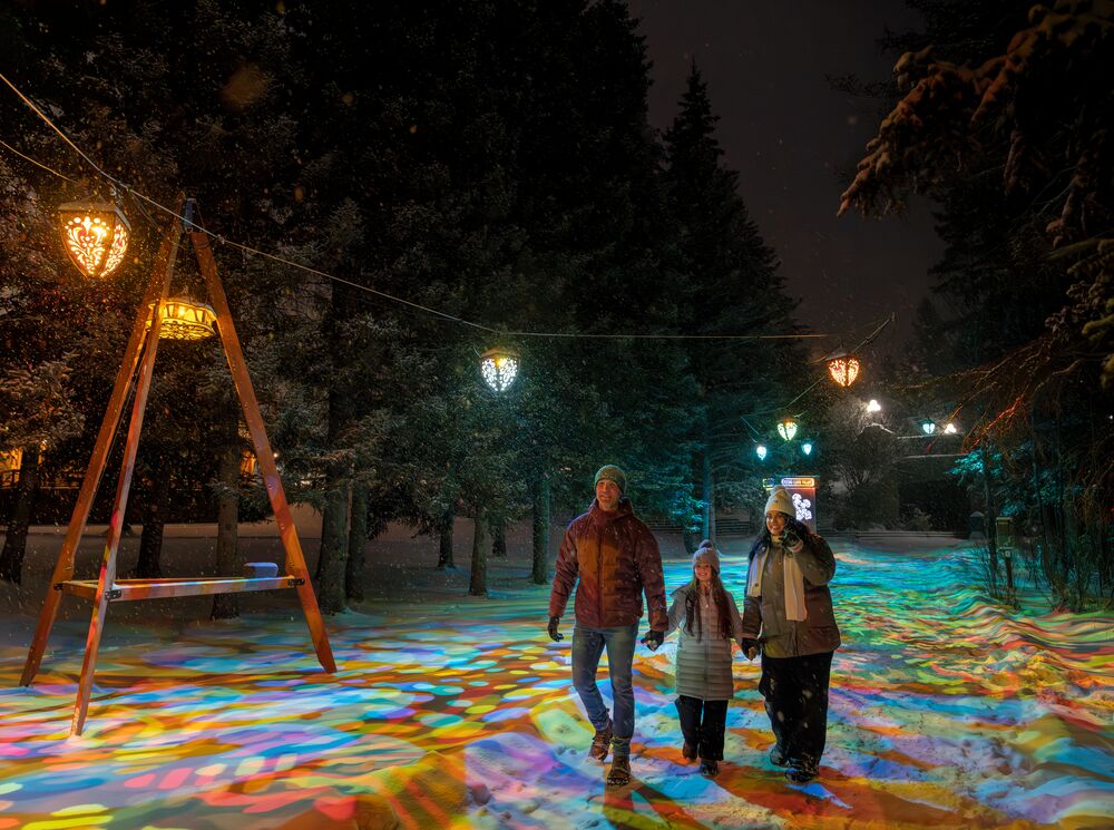 Family walking beneath colourful lantern lights at the Flying Canoe Volant Festival in downtown Banff, a must-visit winter event in Banff National Park celebrating culture, community, and the magic of winter in the Canadian Rocky Mountains.