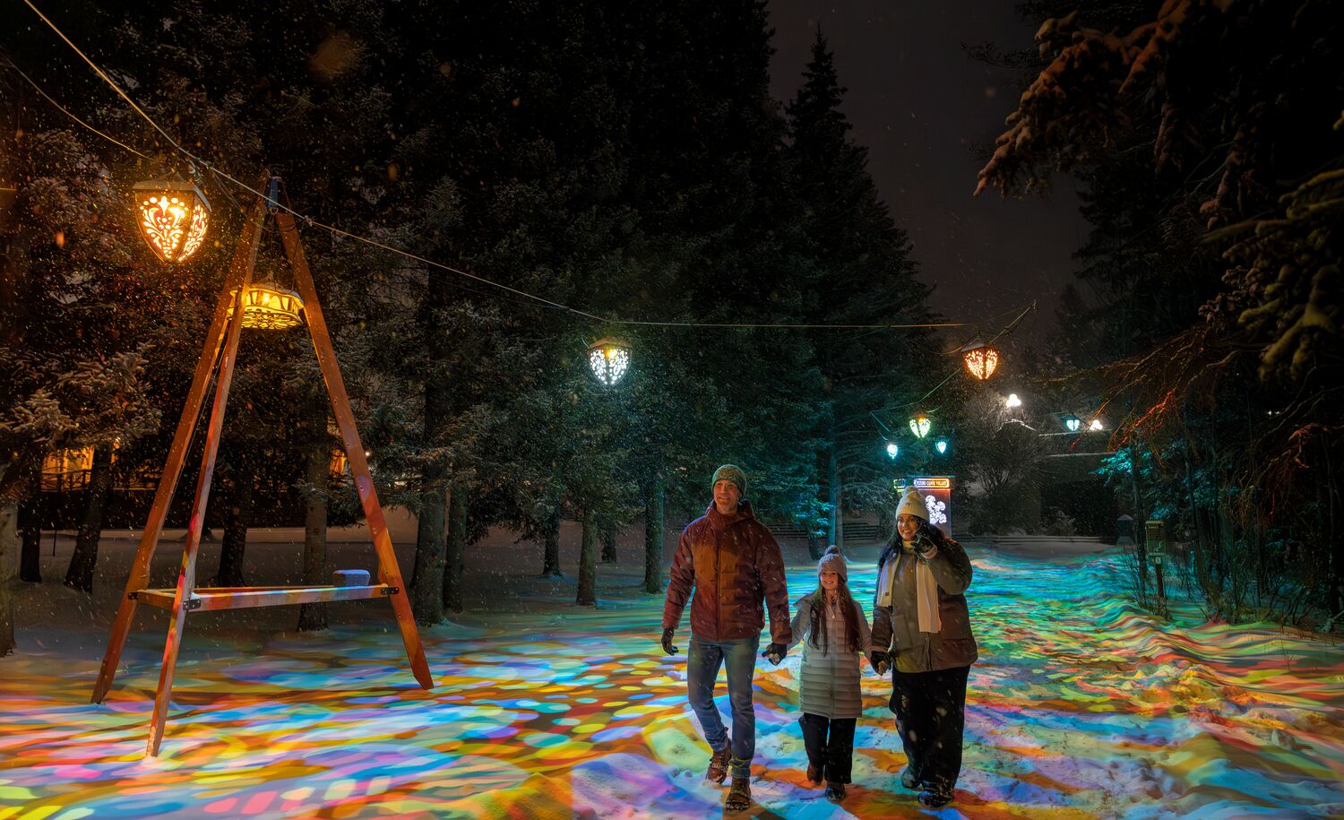 Family walking beneath colourful lantern lights at the Flying Canoe Volant Festival in downtown Banff, a must-visit winter event in Banff National Park celebrating culture, community, and the magic of winter in the Canadian Rocky Mountains.