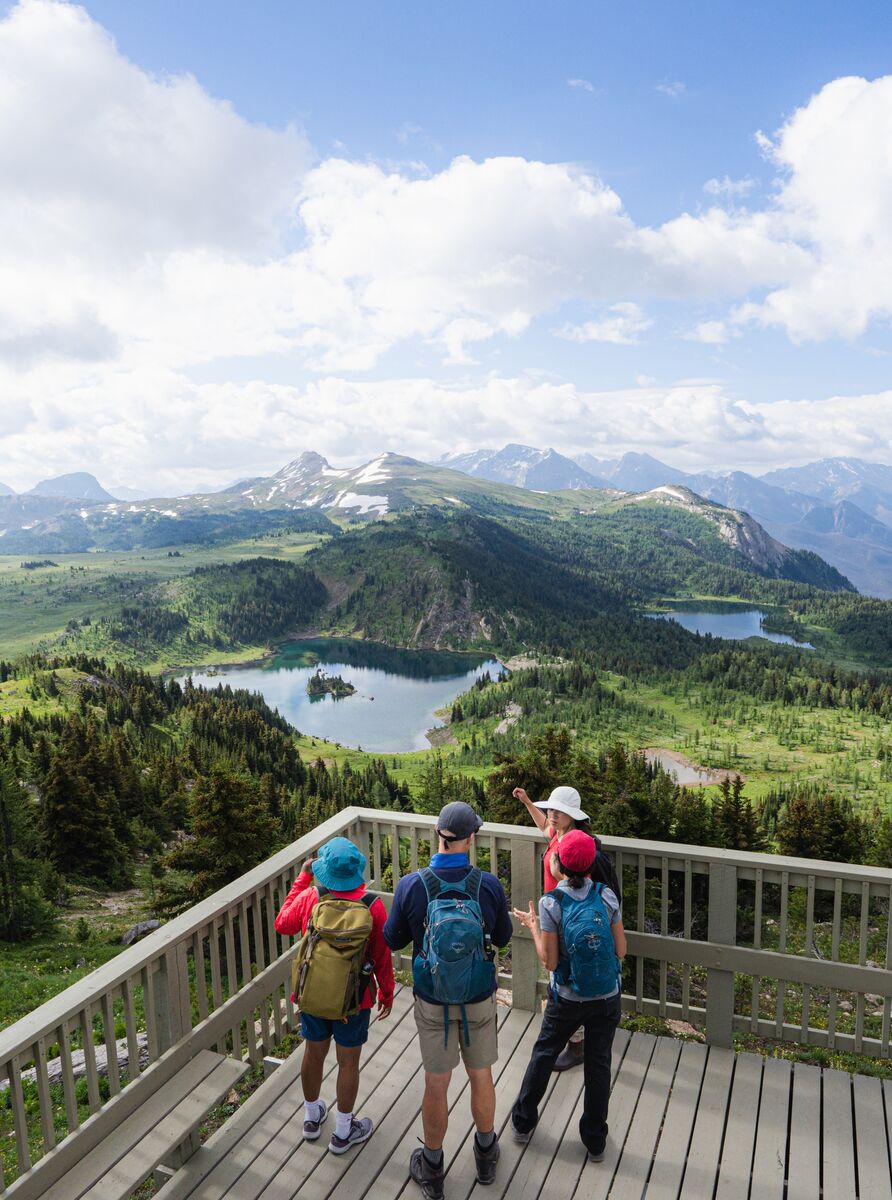 A woman and two children hiking up Sulphur Mountain in Banff National Park with the Banff Gondola in the background.