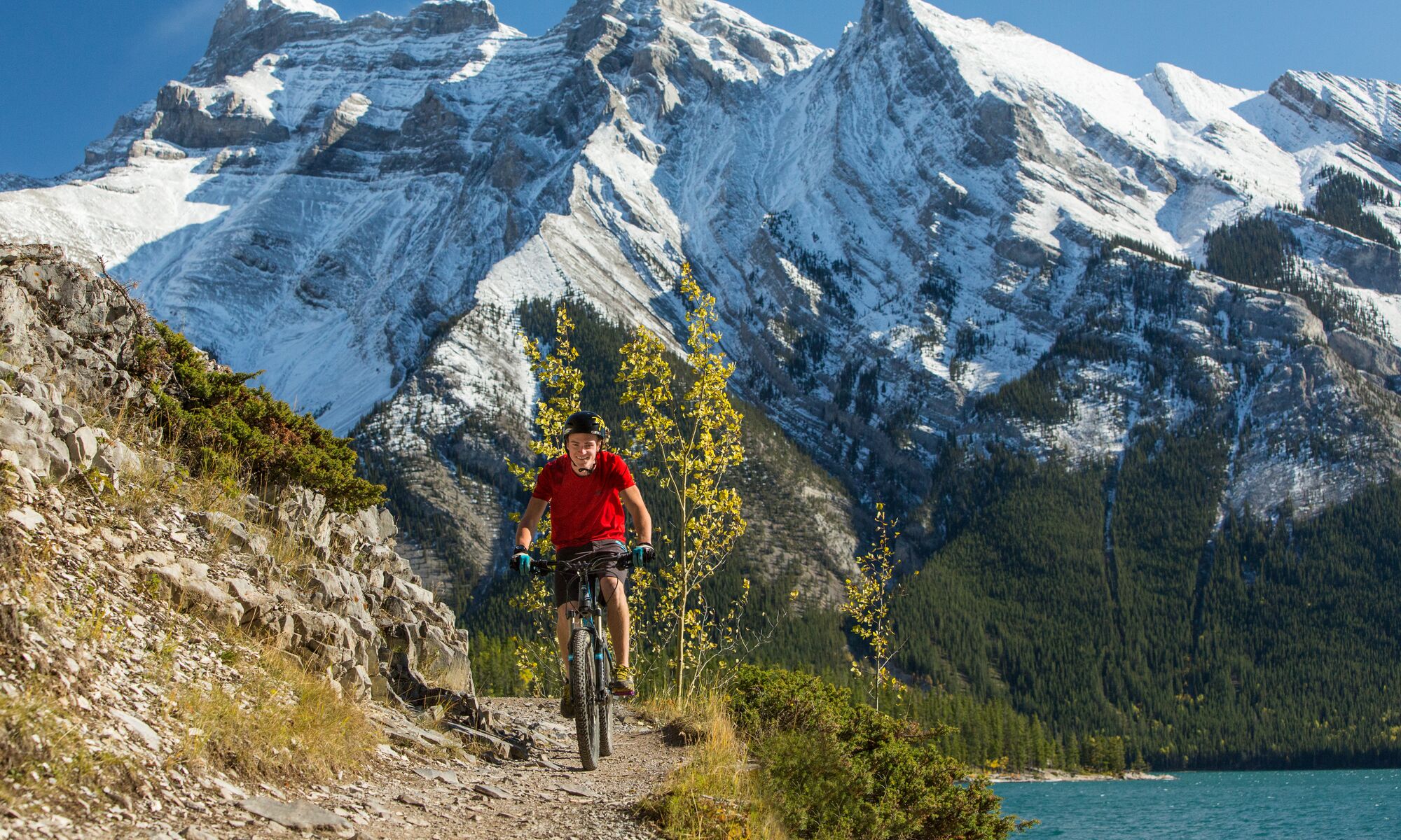 A mountain biker rides a trail at Lake Minnewanka on a bluebird day in Banff National Park.