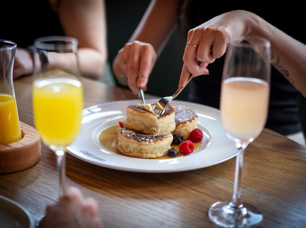A person eating pancakes with a mimosa at a restaurant in Banff National Park