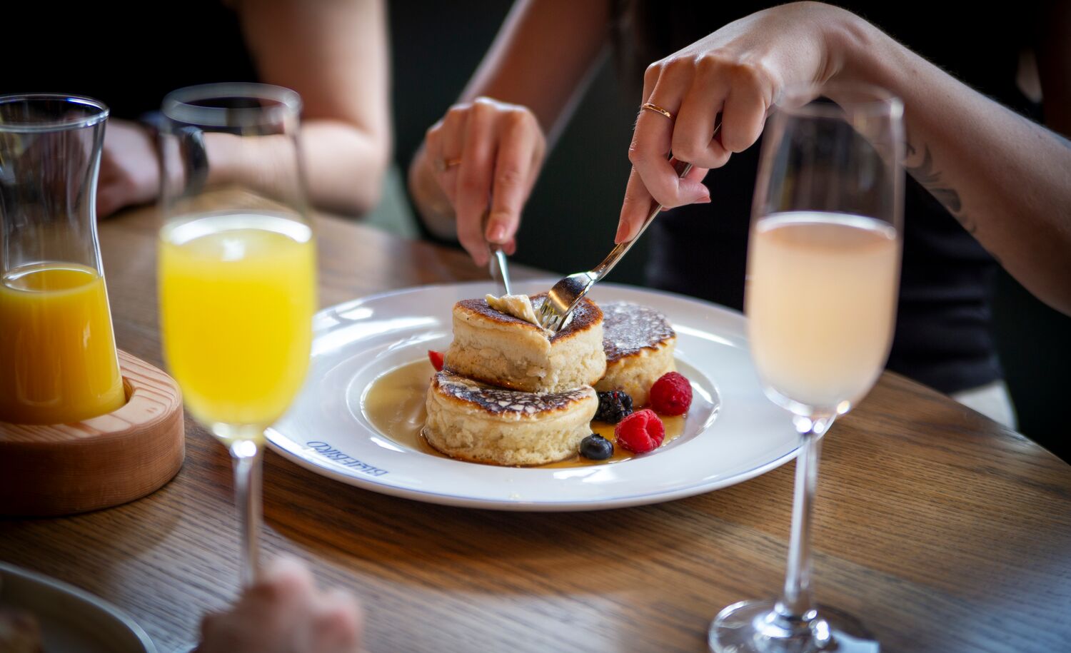 A person eating pancakes with a mimosa at a restaurant in Banff National Park