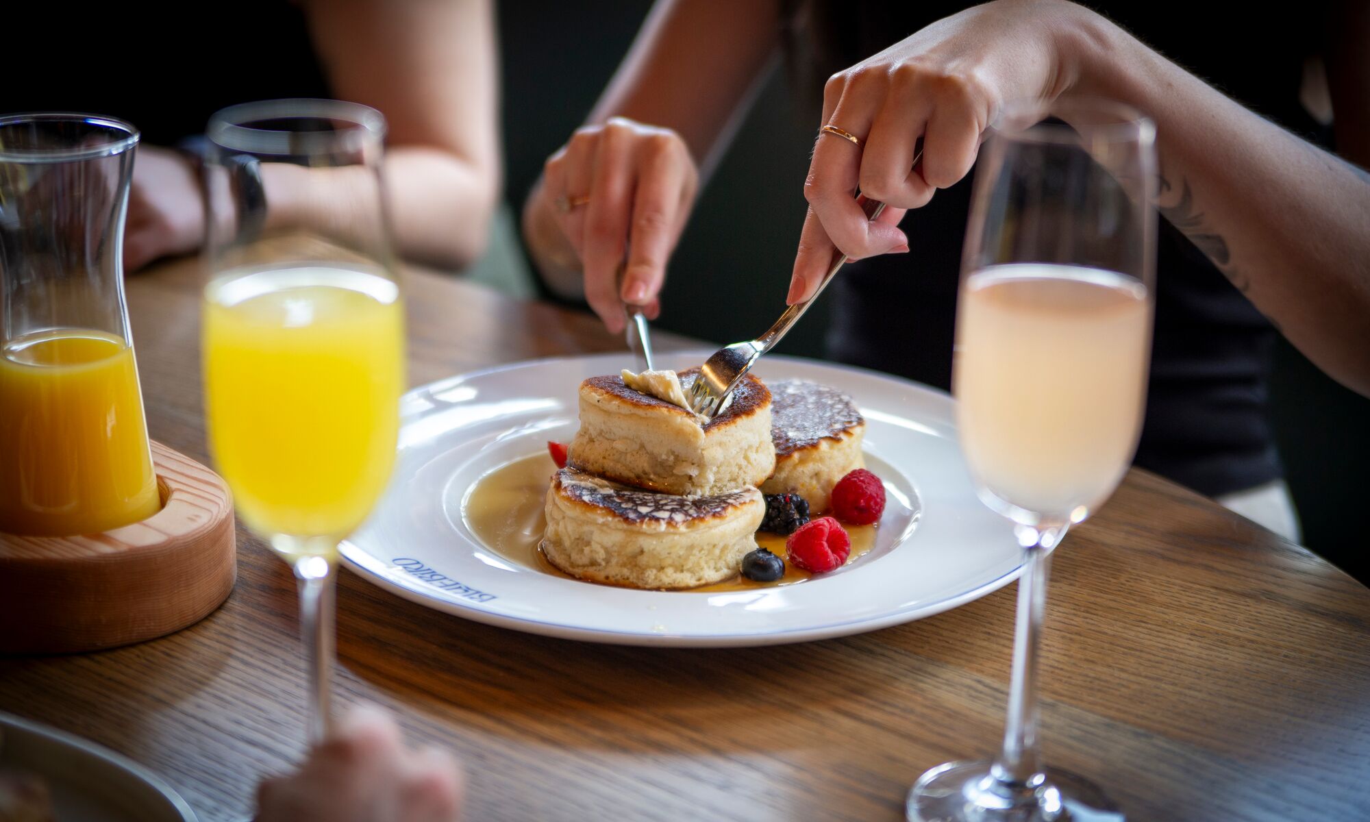 A person eating pancakes with a mimosa at a restaurant in Banff National Park