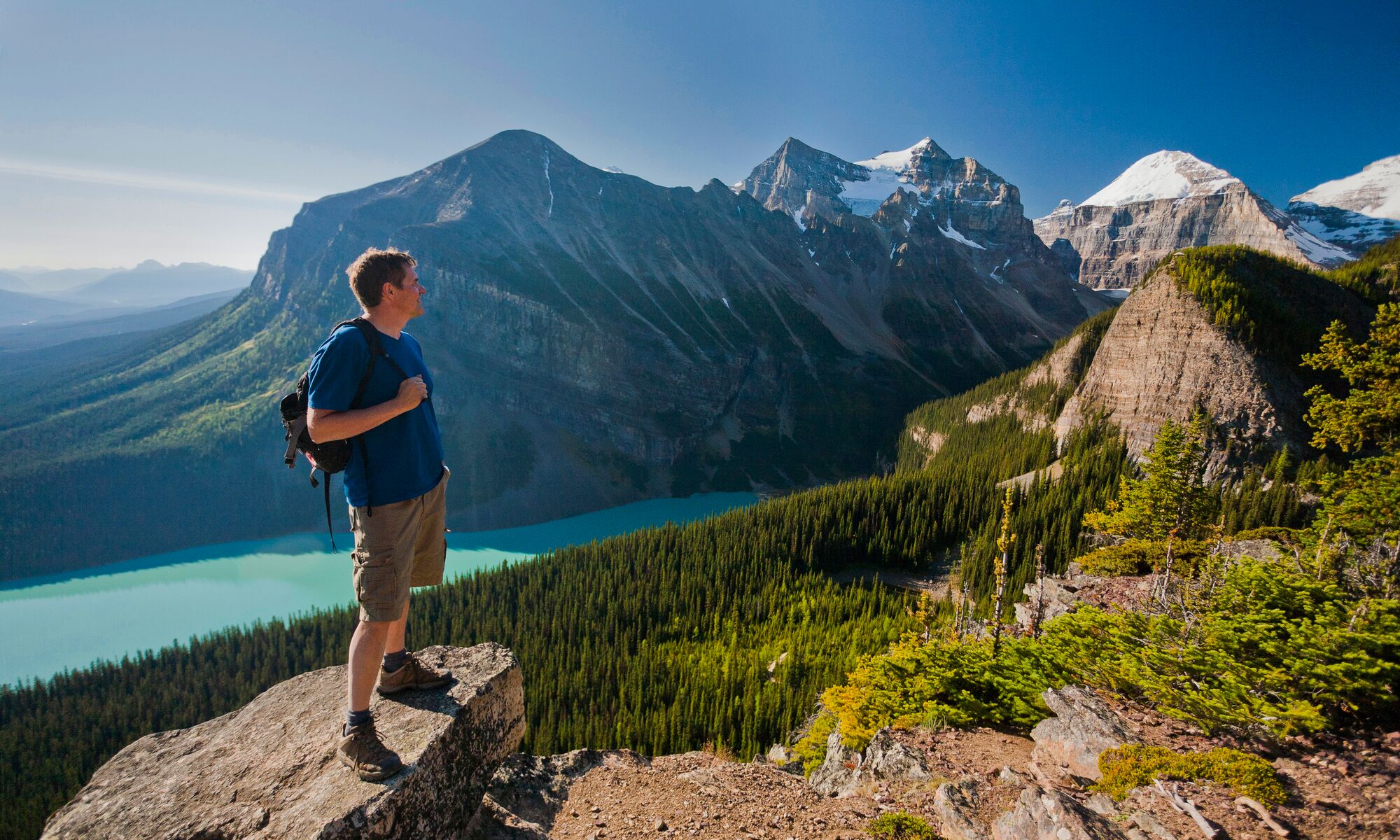 A person stands on a rock at Little Beehive in Lake Louise, one of Banff National Park's best hiking trails.