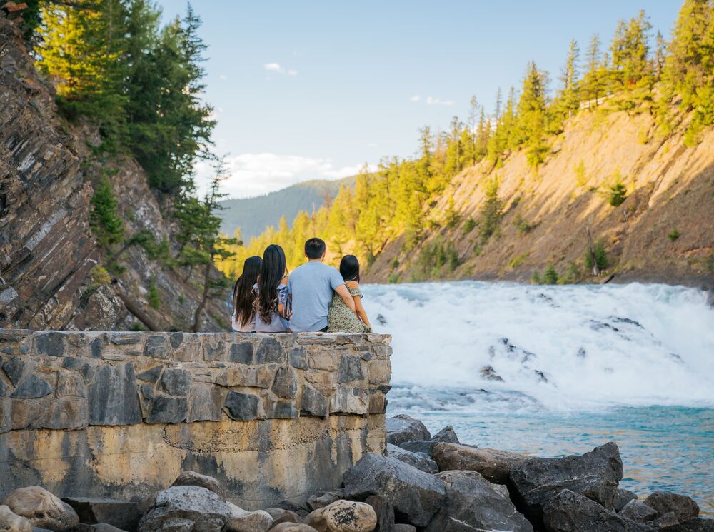 A family of four sitting looking at Bow falls in Banff National Park