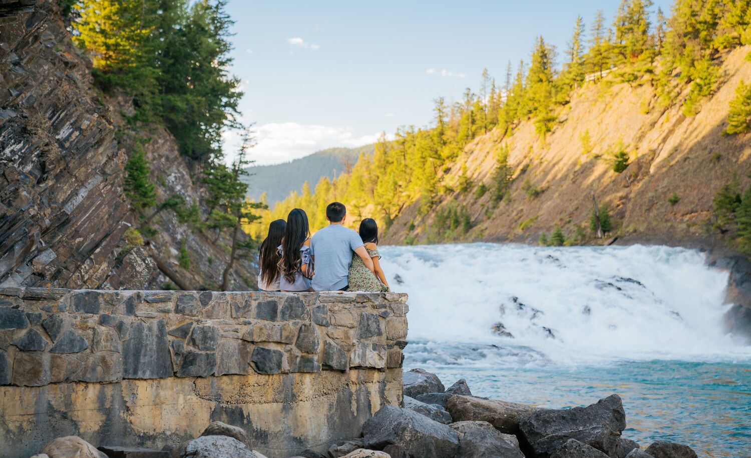 A family of four sitting looking at Bow falls in Banff National Park