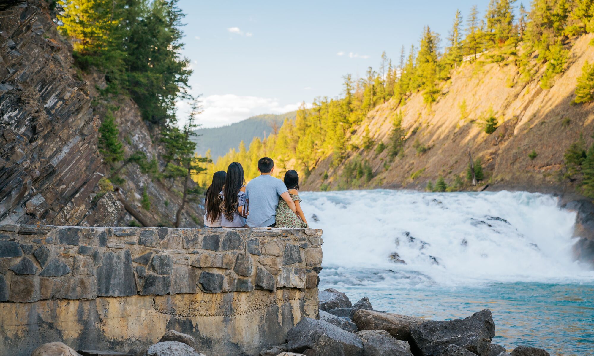 A family of four sitting looking at Bow falls in Banff National Park
