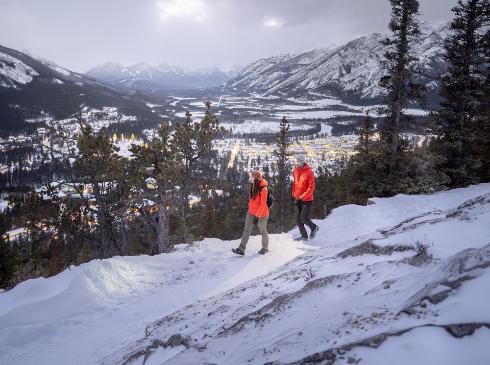 Two people hiking at blue hour on Tunnel Mountain in Banff National Park.