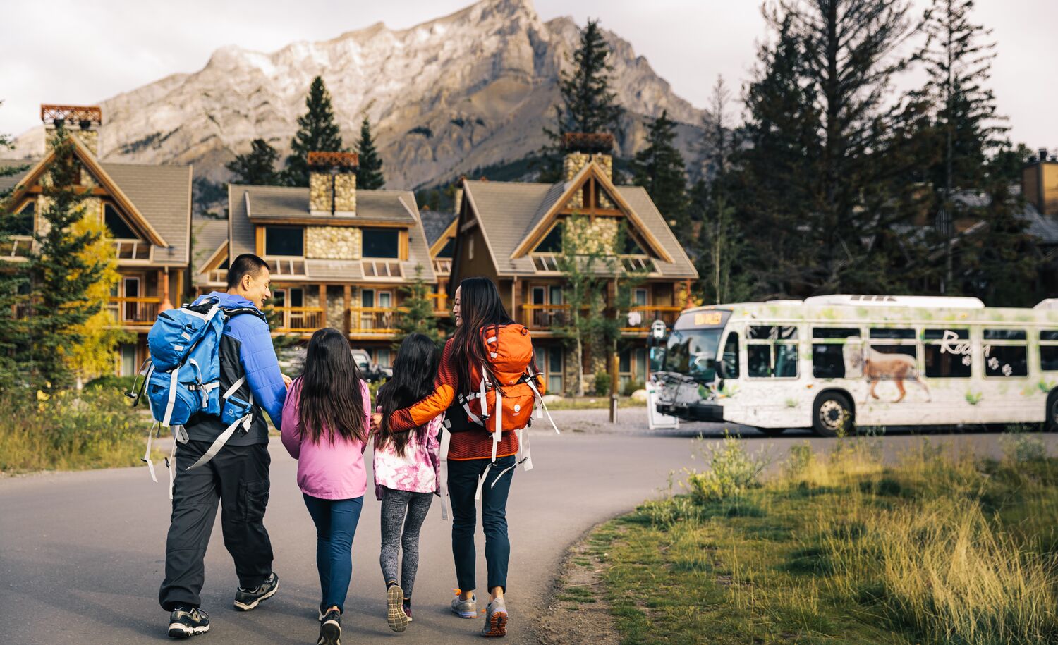 A family of four walking to a Roam bus in Banff National Park