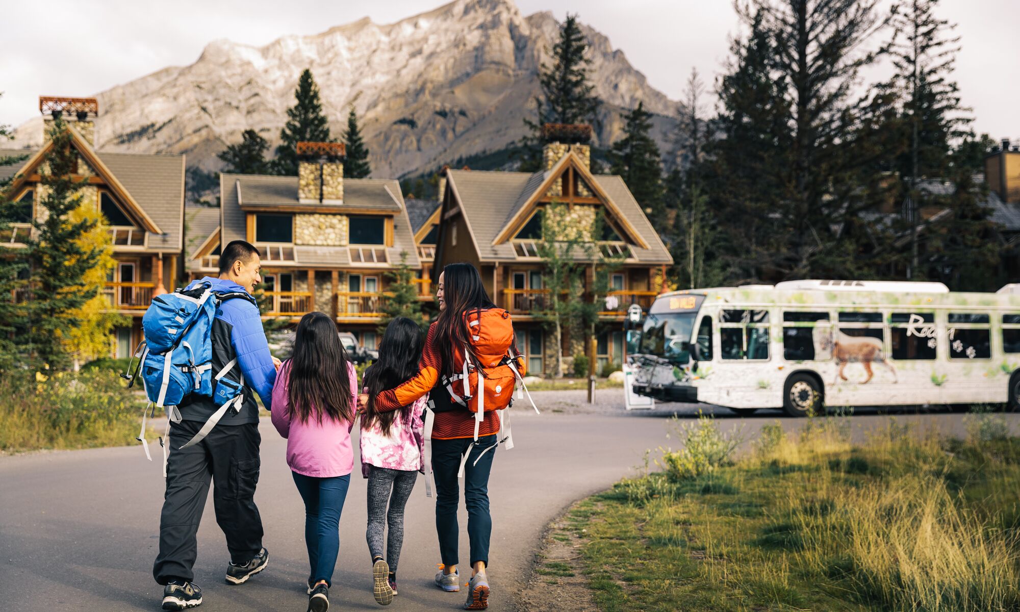A family of four walking to a Roam bus in Banff National Park