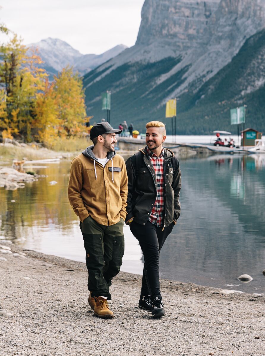 Two people walk along the Lake Minnewanka Lakeshore trail on their way to hike in the fall in Banff National Park.