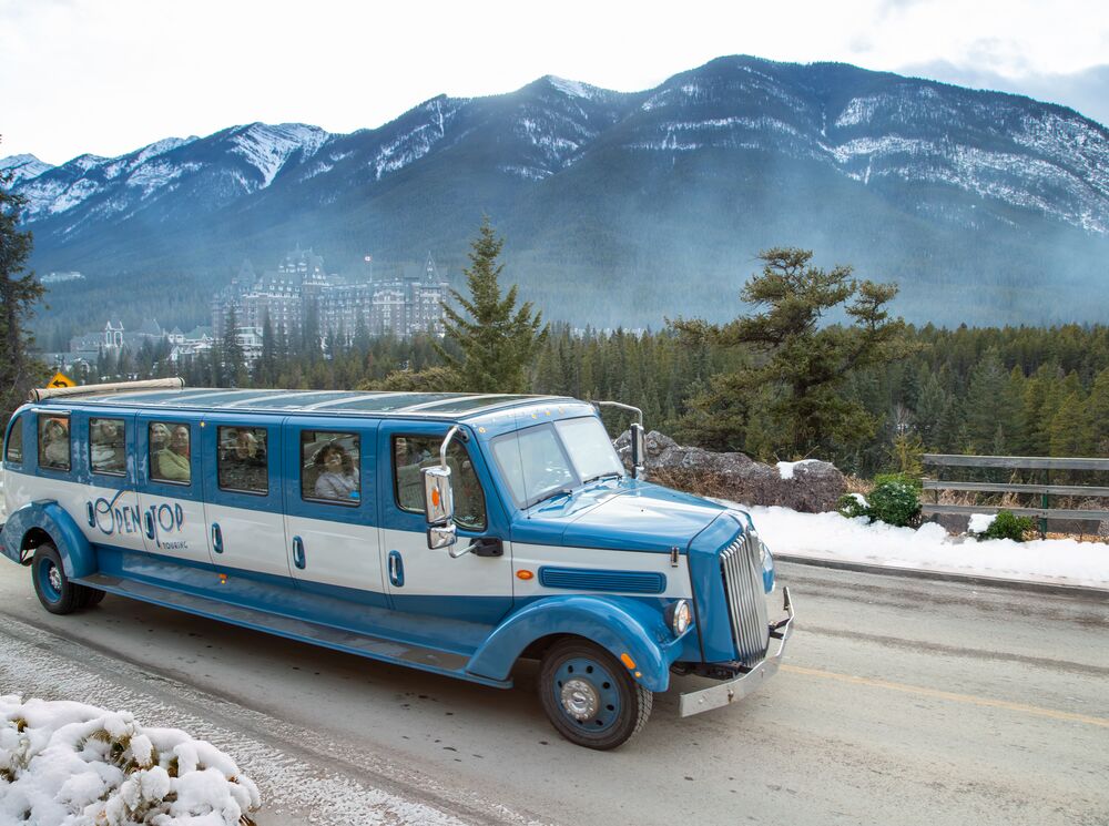 An Open Top Touring bus driving past surprise corner in winter in Banff National Park