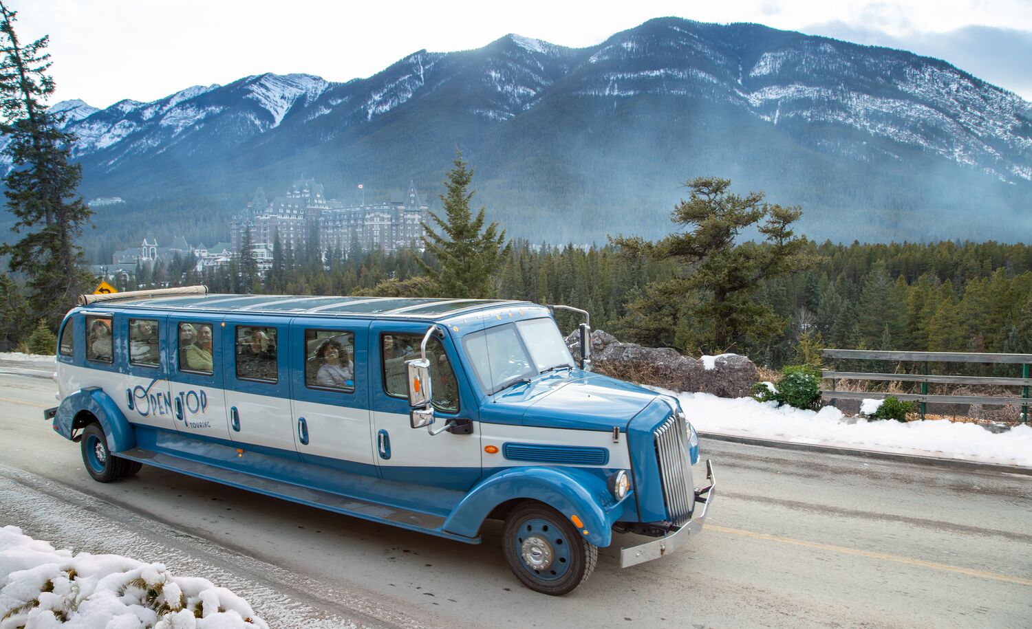 An Open Top Touring bus driving past surprise corner in winter in Banff National Park