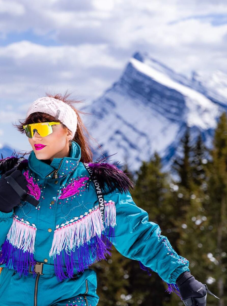 A skier stands on a slope at Mt. Norquay with Mount Rundle behind them in Banff National Park.