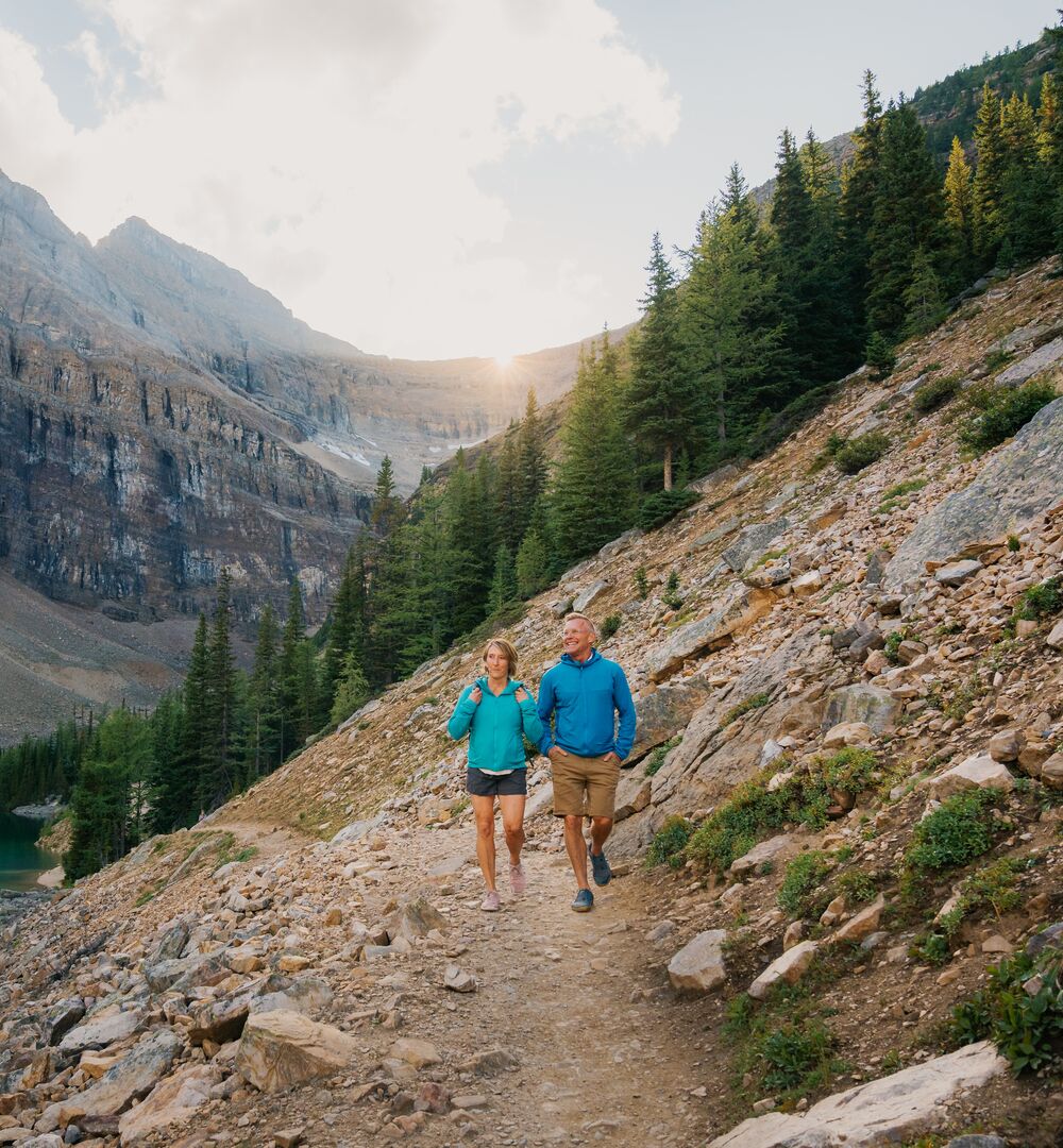 Two people hiking in Banff National Park in Lake Louise on the Lake Louise Tea House Trail to Lake Agnes.