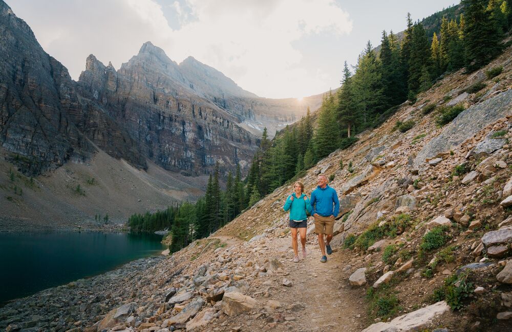 Two people hiking in Banff National Park in Lake Louise on the Lake Louise Tea House Trail to Lake Agnes.