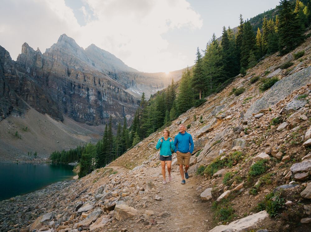 Two people hiking in Banff National Park in Lake Louise on the Lake Louise Tea House Trail to Lake Agnes.