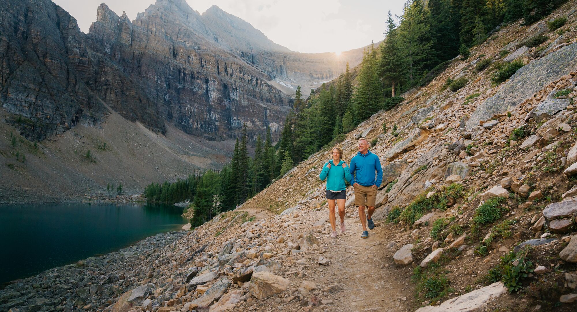Two people hiking in Banff National Park in Lake Louise on the Lake Louise Tea House Trail to Lake Agnes.